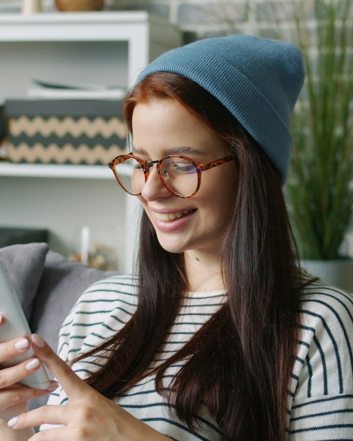 Une femme en bonnet qui sourit à son téléphone en apprenant avec Astra Trainer