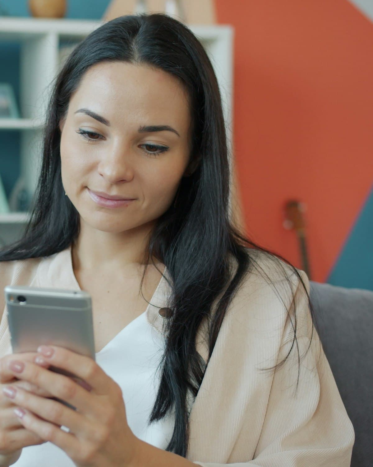 Una mujer sonríe a su teléfono en el sofá mientras aprende con Astra Trainer