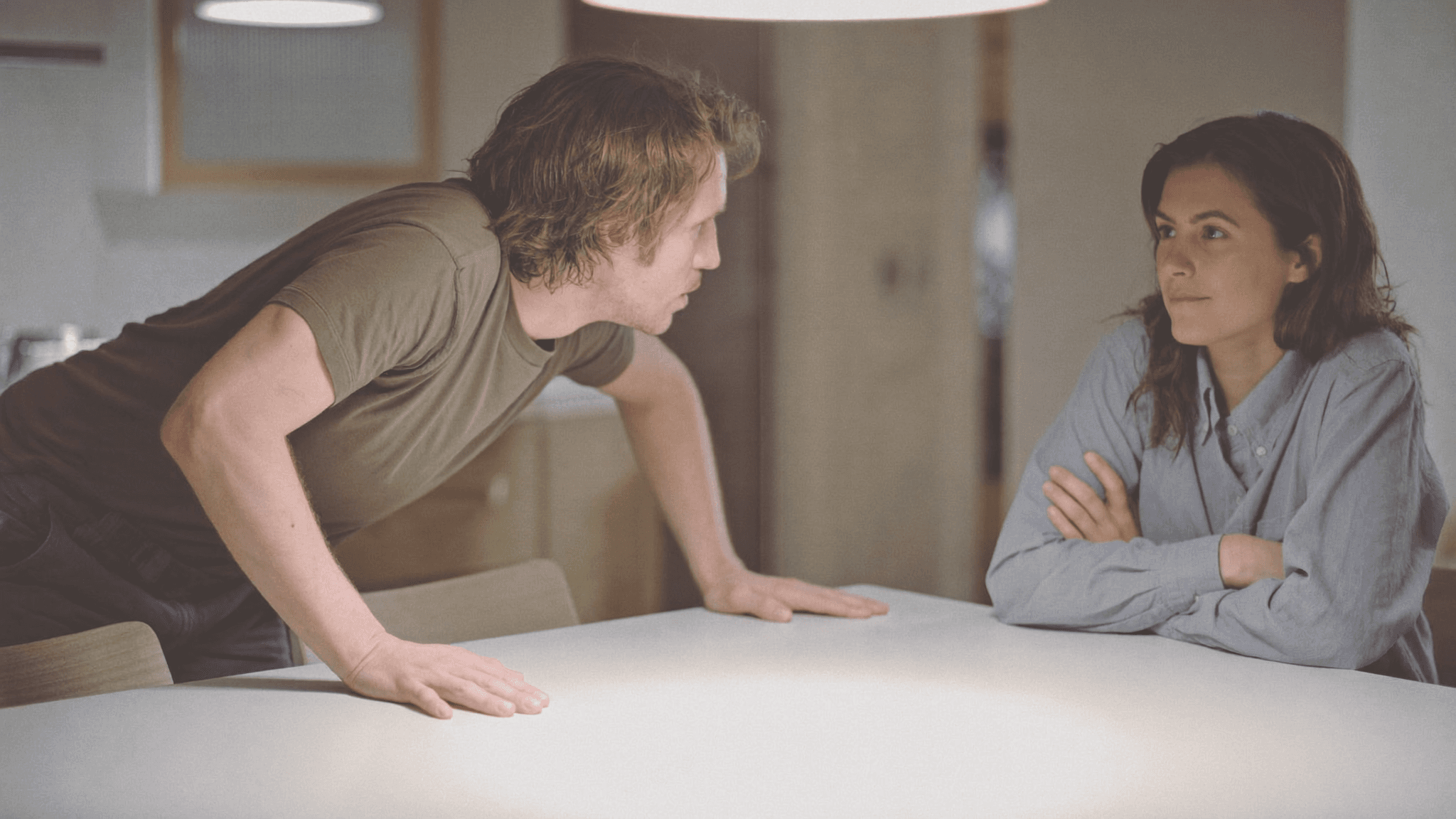 Two people at a table — one leaning in, one leaning back