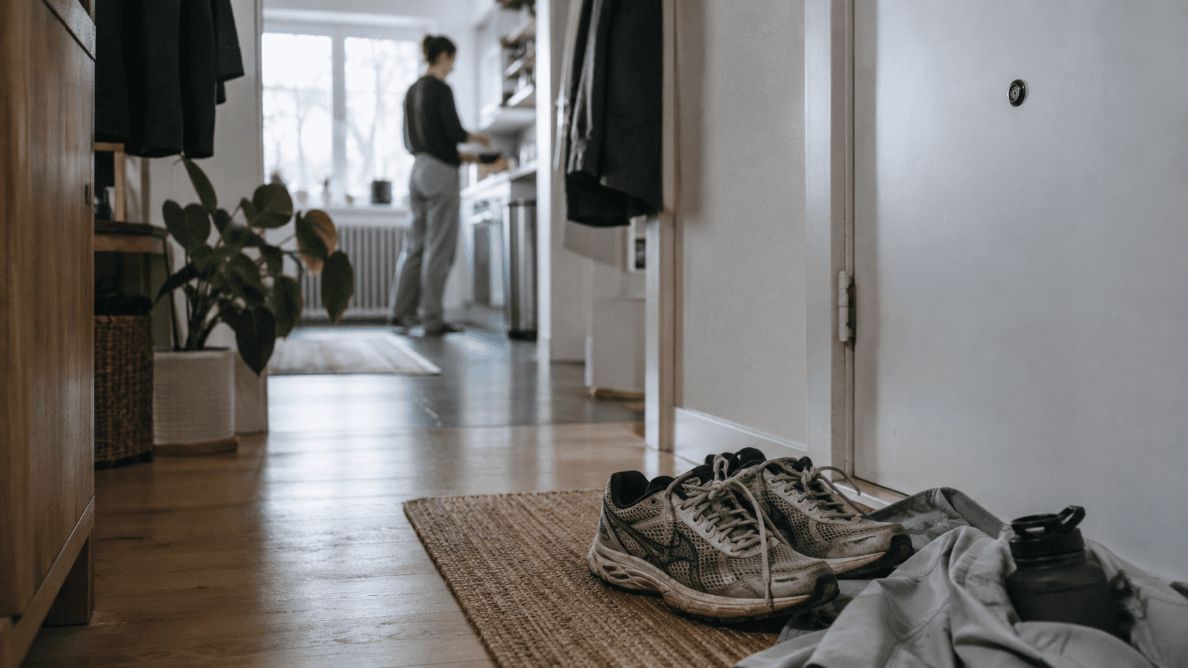 Ein Paar Laufschuhe steht seit mehreren Tagen unberührt neben der Haustür im Morgenlicht