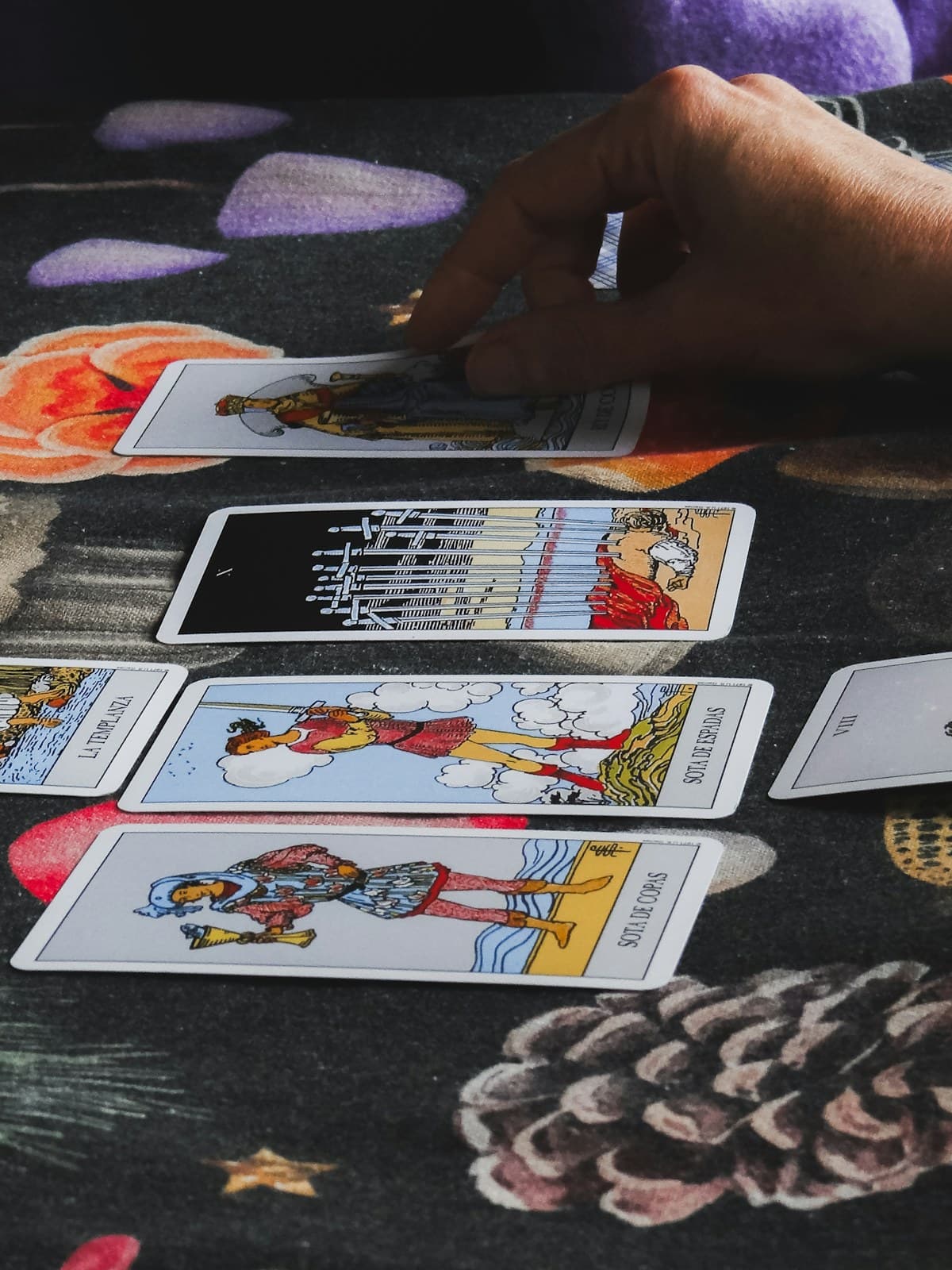 Hands laying tarot cards in a row on a dark cloth during a reading