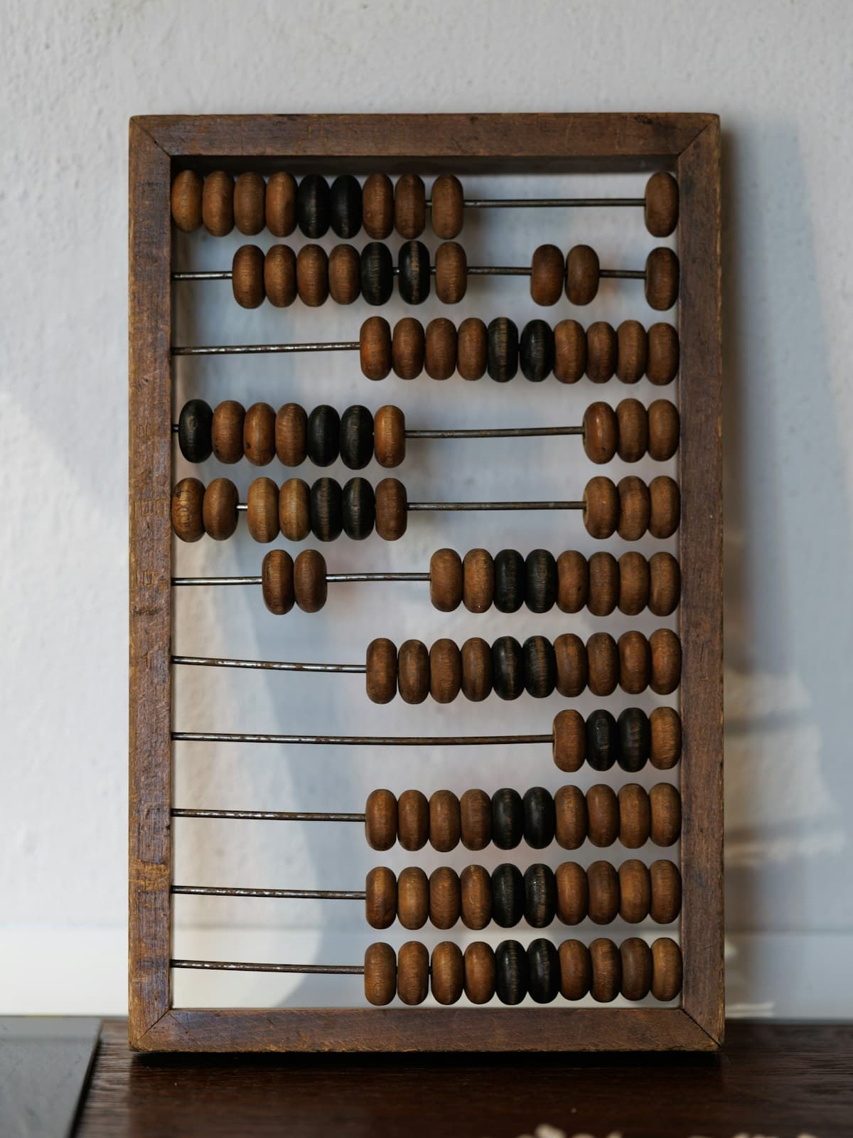 A vintage wooden abacus with dark beads on metal rods