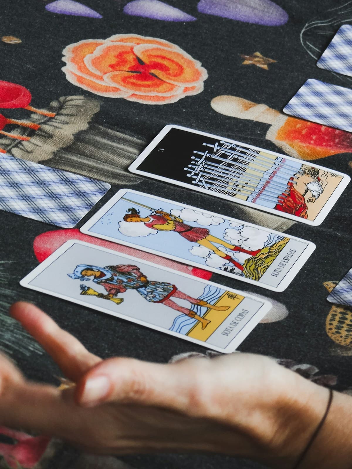Hands laying out tarot cards on a dark patterned cloth