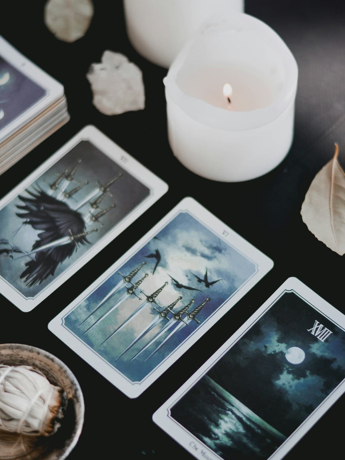 Tarot cards laid out beside a lit candle on a dark surface