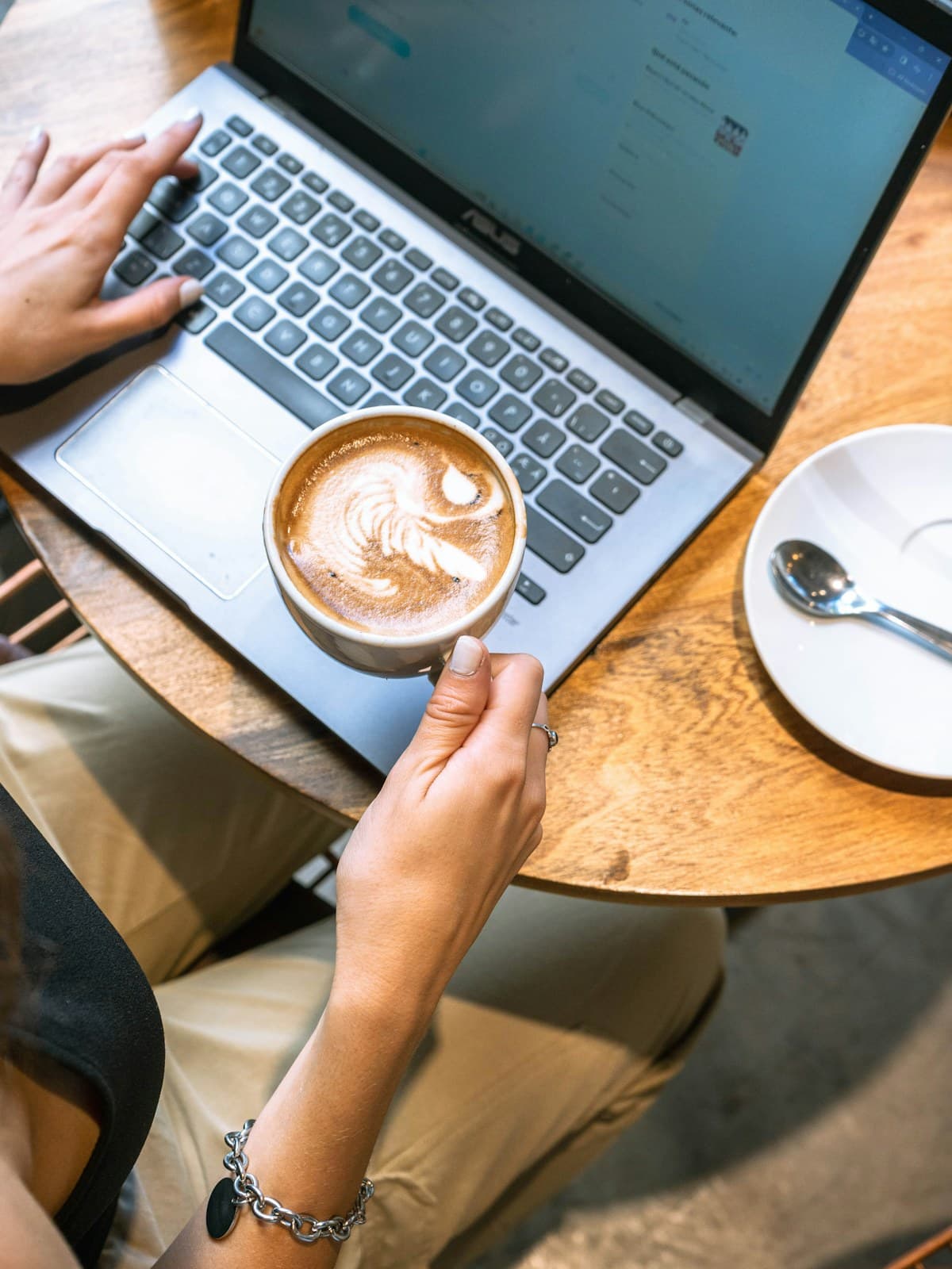 Hands on a laptop keyboard beside a cup of coffee