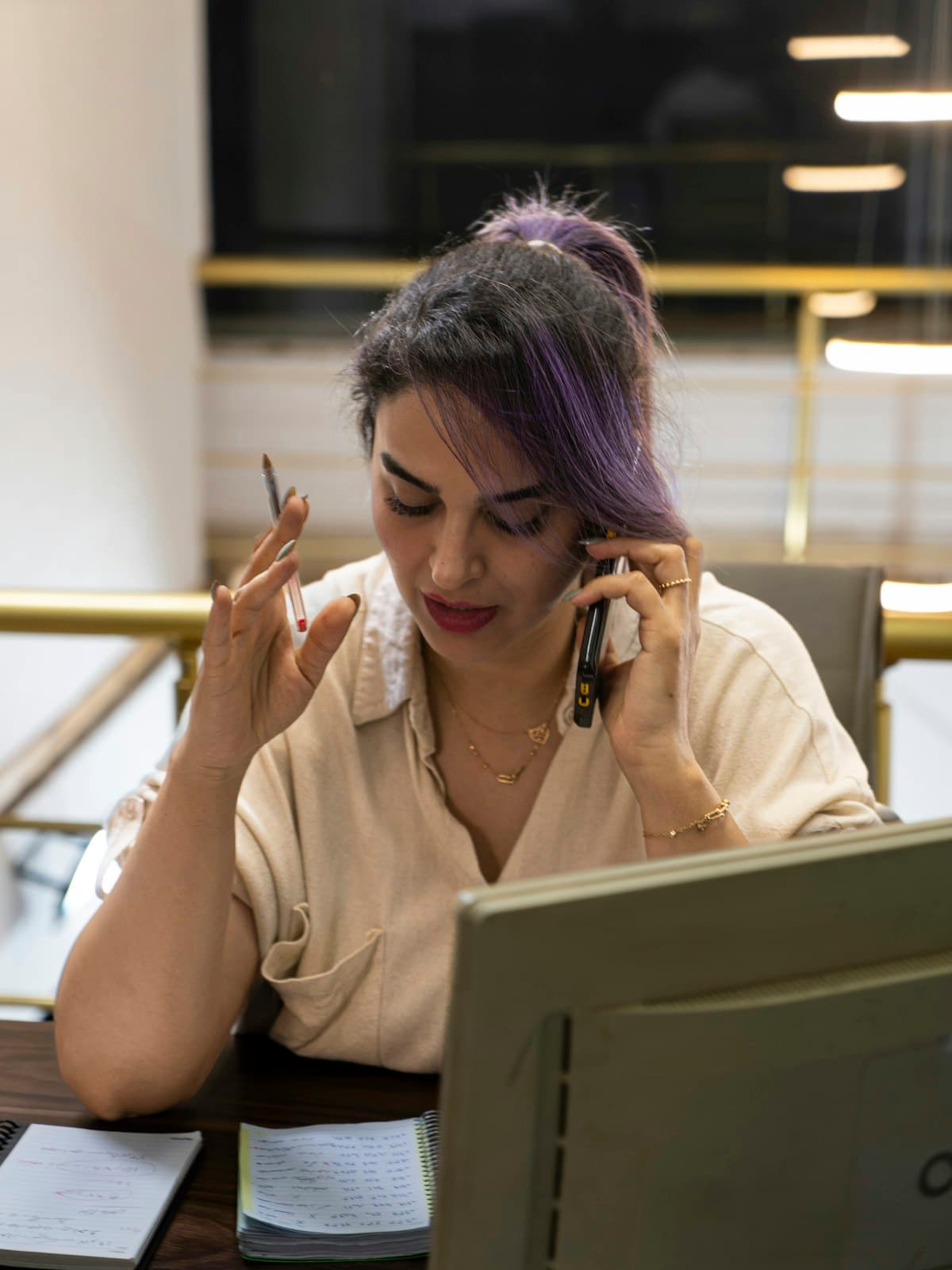 A woman on a phone call at a desk, taking notes