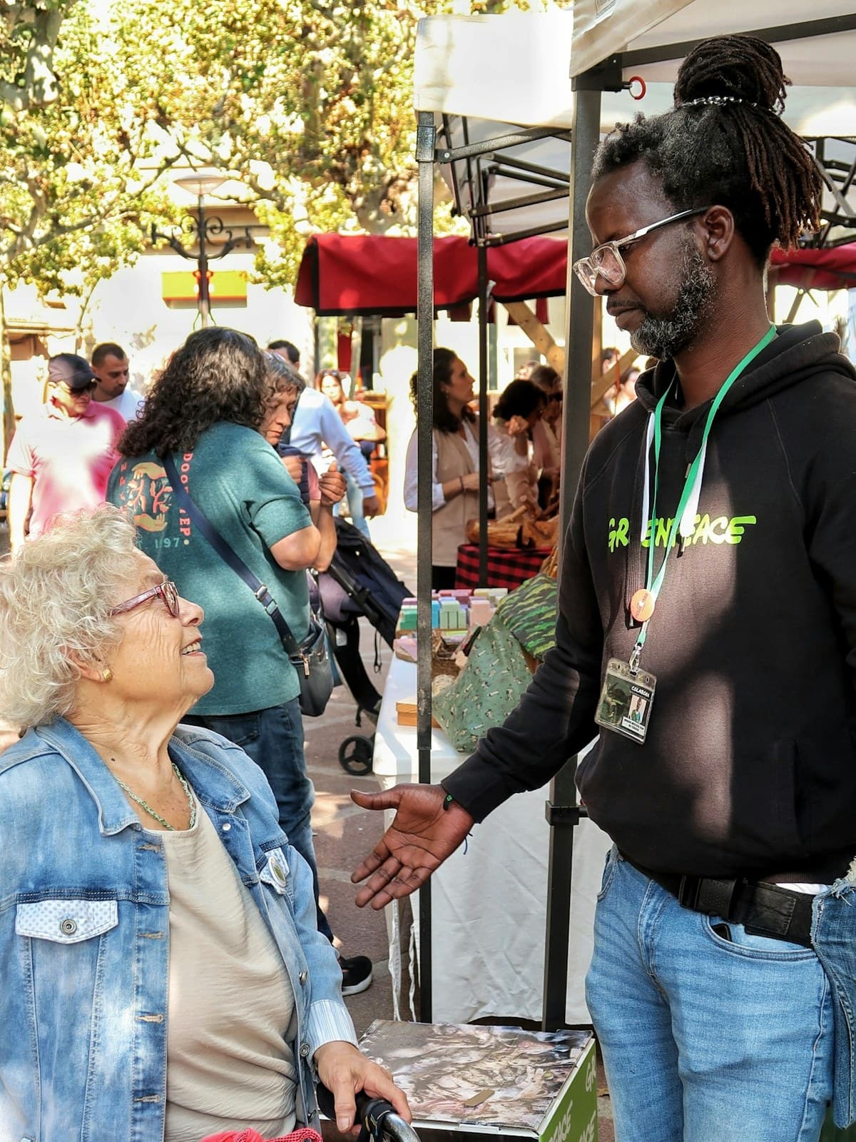 A vendor talking with customers at an outdoor market stall