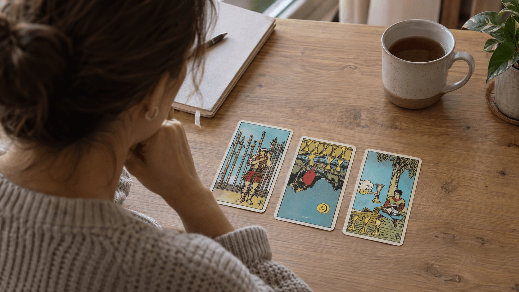 Eine Tarotdeutung mit einer umgekehrten und zwei aufrechten Karten in einer Drei-Karten-Legung auf einem Holztisch.
